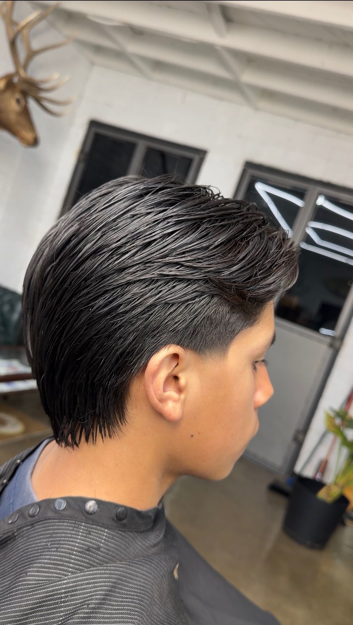 Young man with freshly styled slicked-back undercut haircut at a barbershop