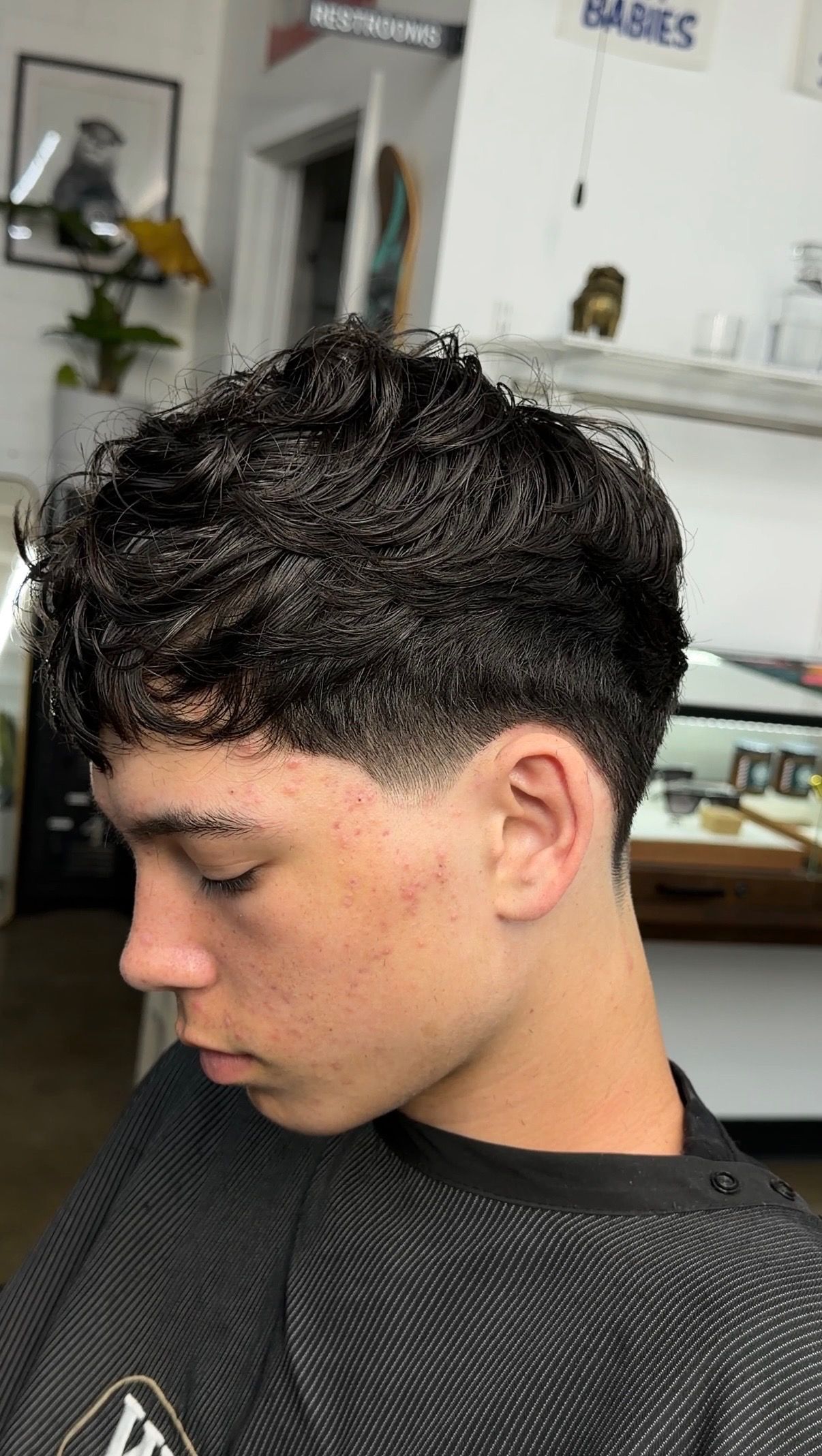 Young man with textured crop fade haircut sitting in barbershop chair