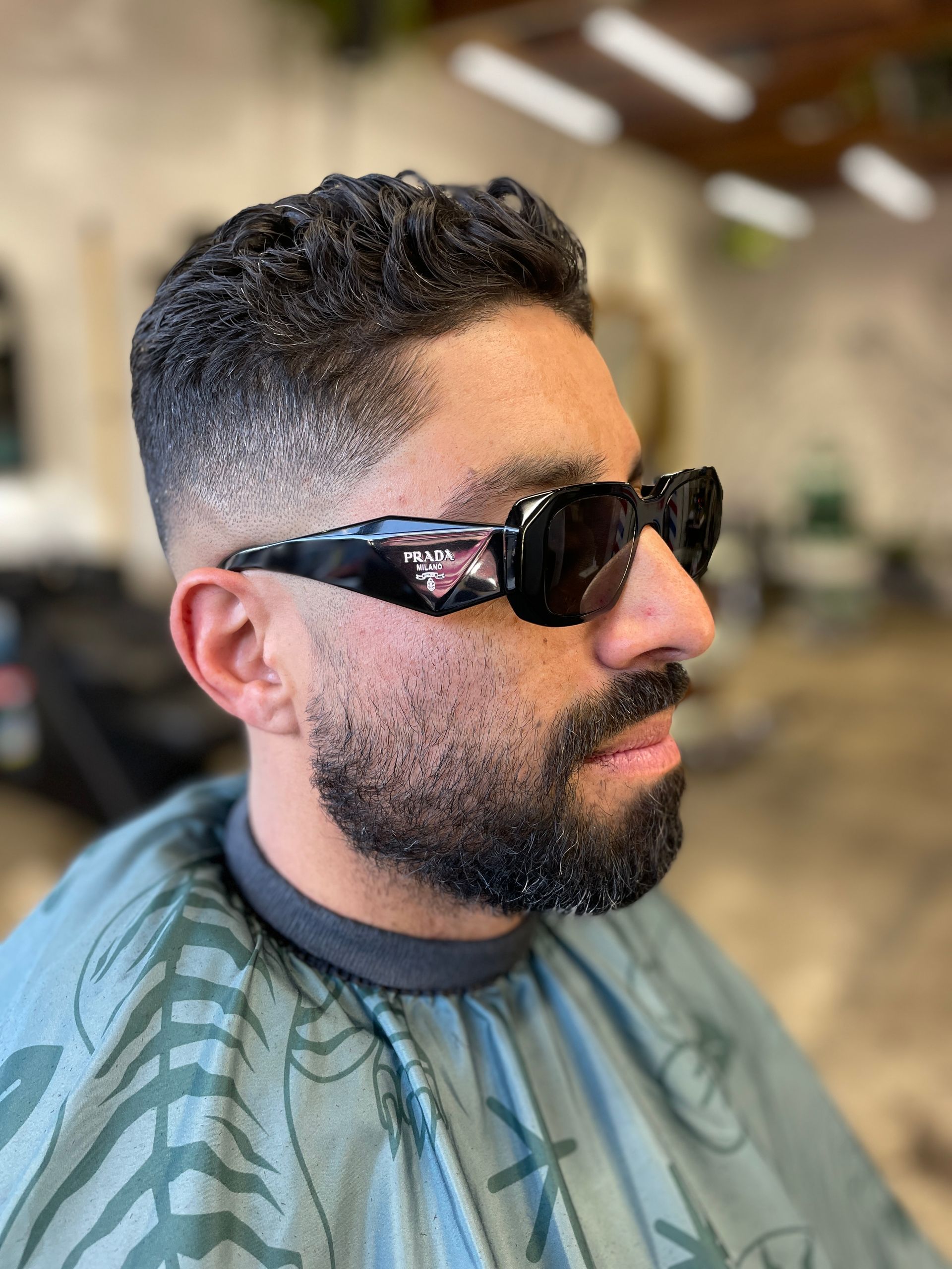 Man wearing Prada sunglasses sits in barber chair after fresh fade haircut