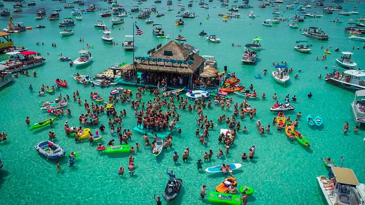 Aerial view of the Crab Island sandbar with the floating bar and boats anchored in emerald water