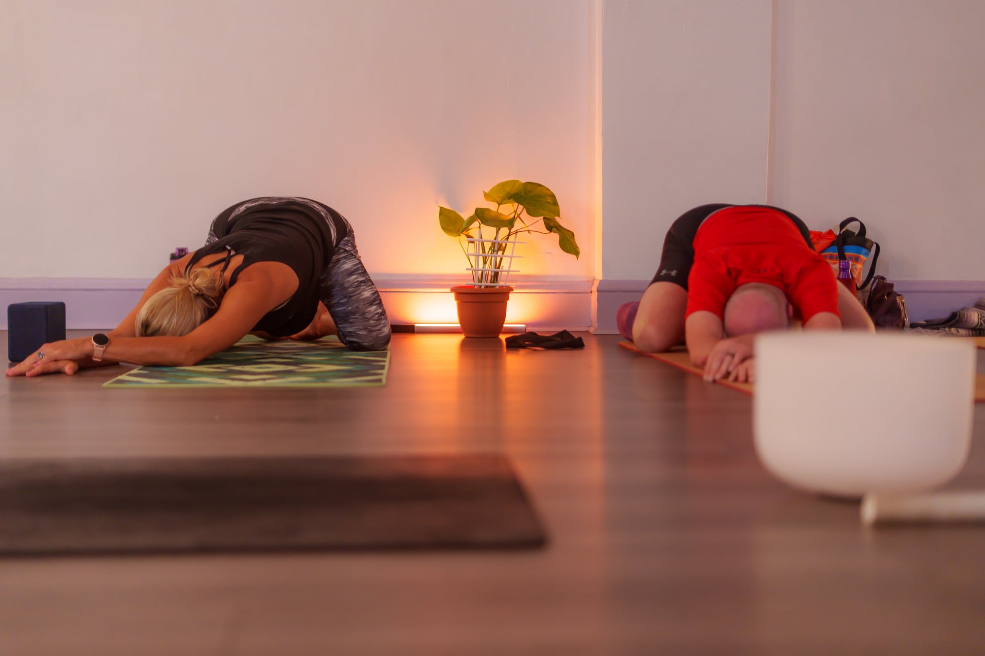 Students resting in child's pose beside a singing bowl